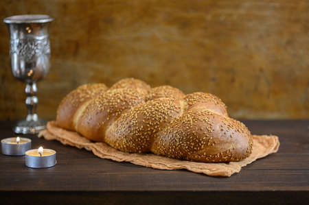 Shabbat Shalom challah bread, shabbat wine and candles on brown wooden table.
