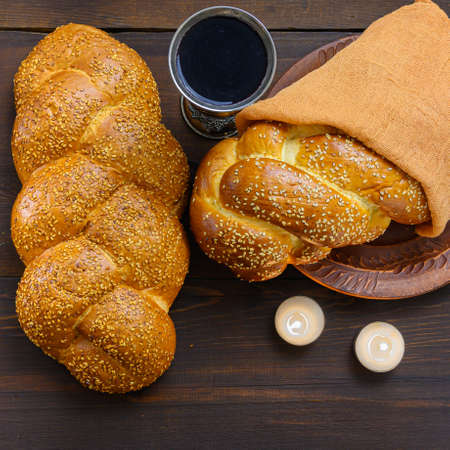 Shabbat Shalom challah bread, shabbat wine and candles on brown wooden table. Top view.の写真素材
