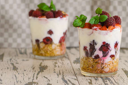Natural Greek yogurt with fresh berries and muesli in a glass. Healthy food, healthy lifestyle, the concept of the menu of sports fitness nutrition. On a light background.の写真素材