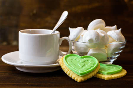 Meringues cookies and a cup of tea on a brown background.の写真素材