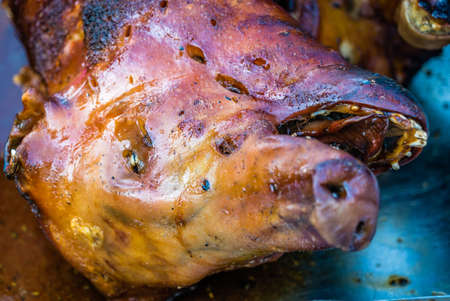 Closeup of the head of a grilled pig on the fire