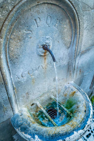 Antic SPQR fountain in Rome with water flowingの写真素材