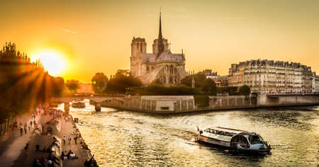 Sunset over Paris wharf and Notre-dame in summer with a peniche boat passing byの写真素材