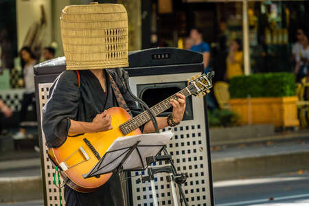 Guitar player in the street with a basket on the headのeditorial素材