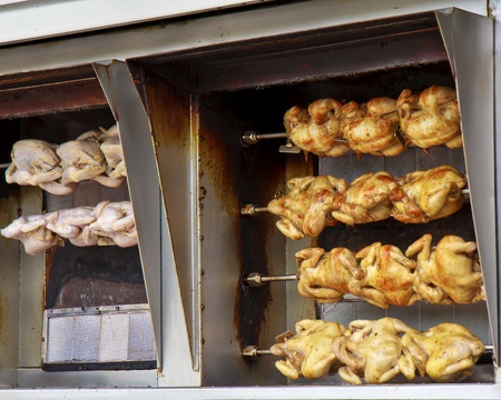 Rows of chickens cooking on a rotisserie.の写真素材