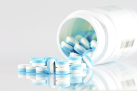 A half of blue and white pills over white background.