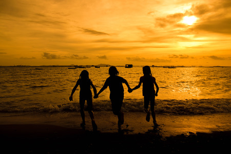 group of happy young girl running  at the beach on beautiful summer sunset.の写真素材