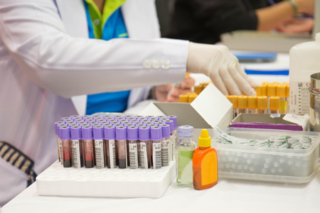 a nurse arranges test tubes with blood on a tray.