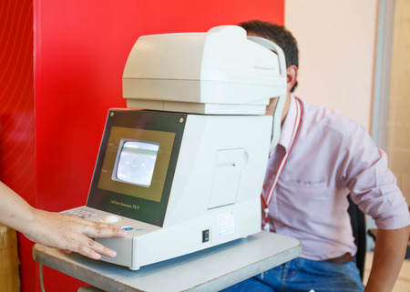 Young Optometrist measuring patient's eye pressure with tonometer.