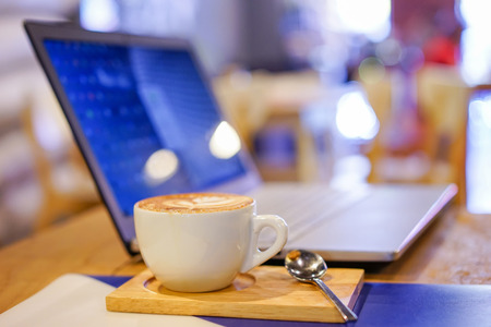 Coffee cup and laptop for business, Selective focus on coffeeの写真素材