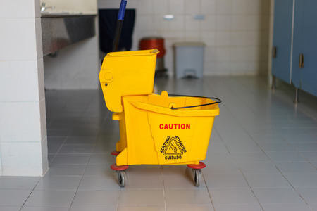 Mop bucket on wet floor in toilet.の写真素材