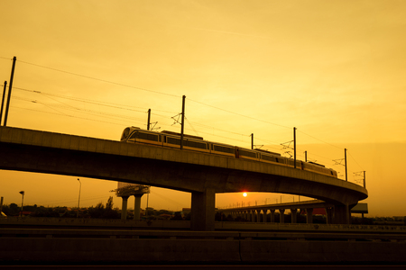 Commuter train on elevated track at sunsetのeditorial素材