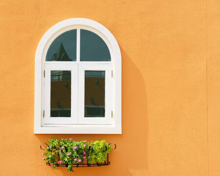 White window and flower hanging with orange wallの写真素材