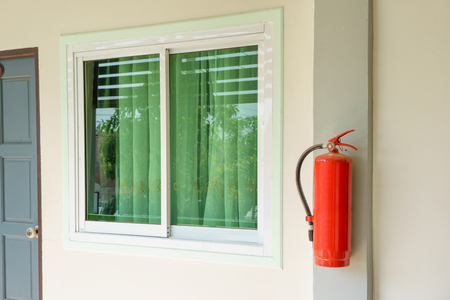 Fire extinguisher in front of room at apartmentの写真素材