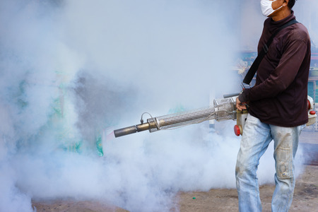 Worker fogging drain at residential area with insecticides to kill aedes mosquito.の写真素材