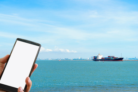 Hand holding smart phone at Container cargo freight ship.の写真素材