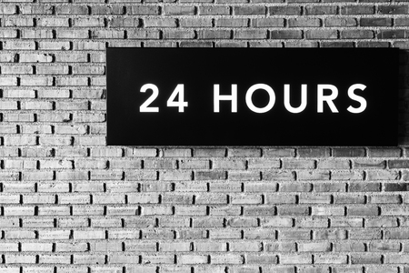 Twenty four hours glowing sign on  brick wall, Black and white styleの写真素材