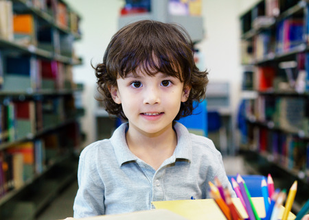 Adorable little child, boy, sitting in a Library, reading booksの写真素材