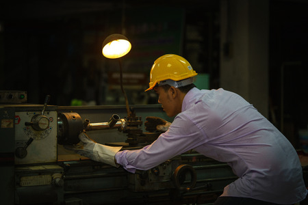 Metal worker looking on Workpiece in workshop.