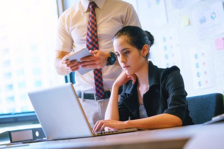 Businesswoman sitting in office table, looking at laptop computer screenの写真素材
