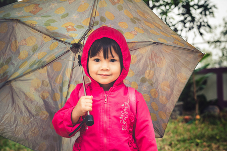 Beautiful little girl with umbrella autumn season.の写真素材