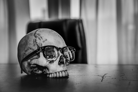 Awesome pile of skull human wear glasses on desk of the bossの写真素材