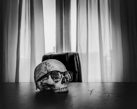 Awesome pile of skull human wear glasses on desk of the boss.の写真素材