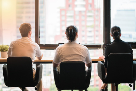 Three business people looking though window.
