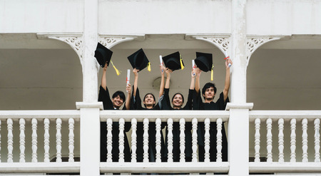 People students in the feeling of happy with the graduation gowns hold the cap.の写真素材