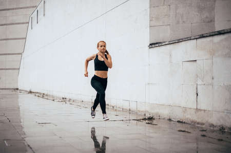 Young woman runs around the city. Running fitness girl in sportswear outdoor.の写真素材