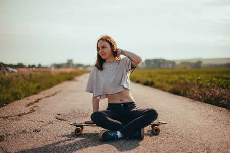 Portrait of a young pretty girl sitting on a longboard. lifestyle photo. woman riding a longboardの写真素材