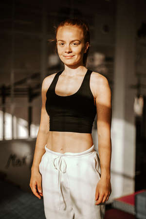 Portrait . Young attractive smiling woman athlete in sport clothes in the gym . sunsetの写真素材