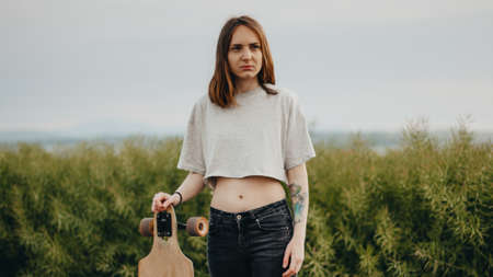 portrait of an ordinary teen girl from the village. The girl holds a longboard in a handの写真素材