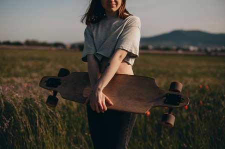 midsection. The tattoo girl holds a longboard in hands. Summer weather.の写真素材