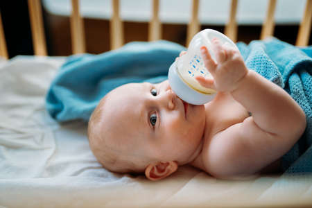 caucasian little baby drinking milk from bottle, close upの写真素材