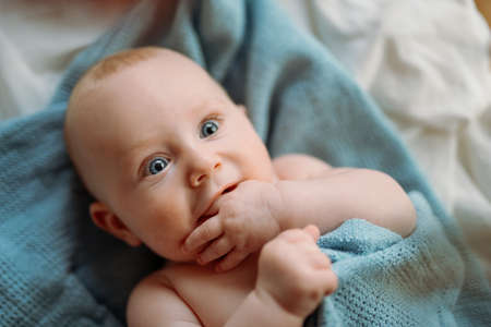 Little cute causian baby boy with blue eyes, smiling at camera, baby lying on his back.の写真素材