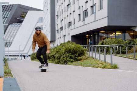 Young man in a helmet rides an electric skateboard. Onewheel rider in an urban background. copy spaceの写真素材