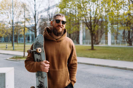 Portrait of a young stylish man holds a skateboard in his hand. Copy spaceの写真素材