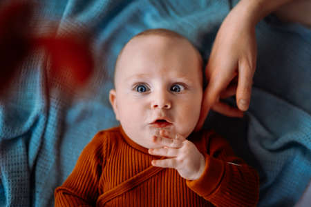 Little boy with blue eyes in the crib. Mom strokes the boy with a finger on his cheekの写真素材