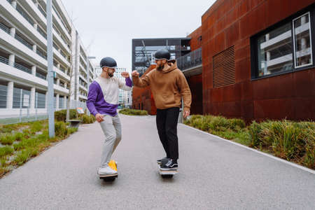 two men on electronic skateboards salute their elbows. the future live style. Urban Backgroundの写真素材