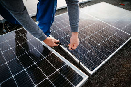 Worker installing solar energy panels. connect two panel together. eco conceptの写真素材