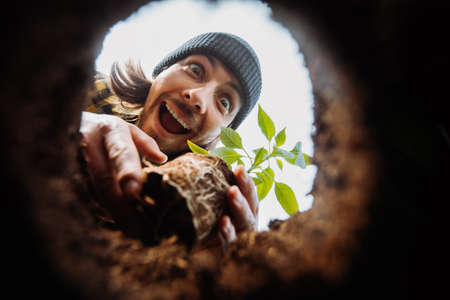 Excited male gardener planting flower. View from hole from bottom up. Looking to the cameraの写真素材