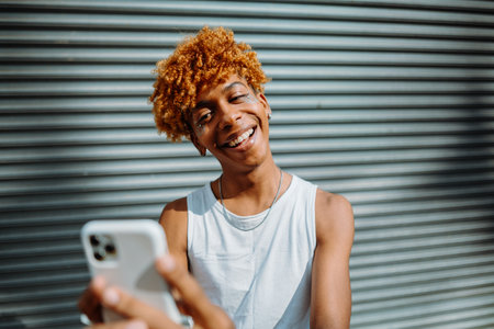 Young dark-skinned man posing at the street and taking selfie in the city backgroundの写真素材