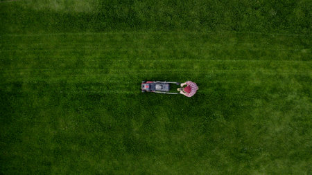 Top view of man mowing green grass in modern garden with lawn mower. Copy spaceの写真素材