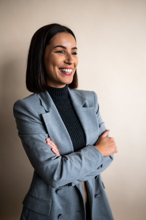 Vertical view of the happy businesswoman posing and smiling on beige studio wall backgroundの写真素材