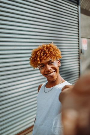 Vertical view of the teenager multiracial guy smiling confident while making selfie by the cameraの写真素材