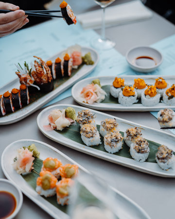 man hands holding sushi and rolls with wooden chopsticks at the restaurantの写真素材
