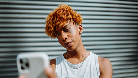 Young dark-skinned man posing at the street and taking selfie in the city backgroundの写真素材
