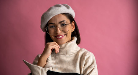 Studio shot of amazing french girl in beret and eyeglasses smiling isolated on pink backgroundの写真素材