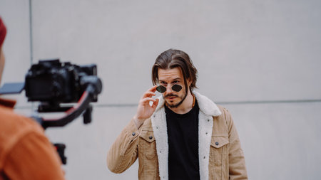 Model man looking through sunglasses and posing to the cameraman in urban streetの写真素材